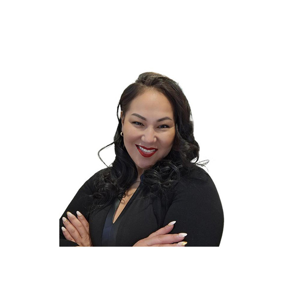 A woman with long, wavy dark hair and red lipstick smiles confidently with arms crossed, wearing a black top against a plain white background.