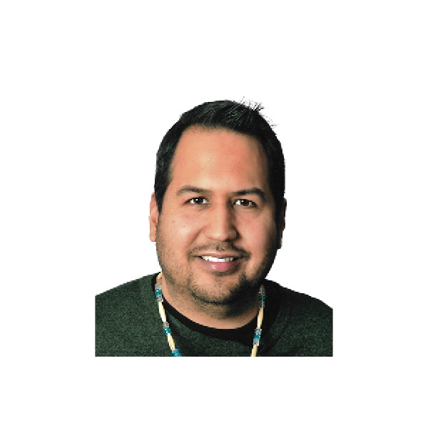 A man with short dark hair, wearing a dark shirt and a beaded necklace, smiles at the camera in front of a plain white background.